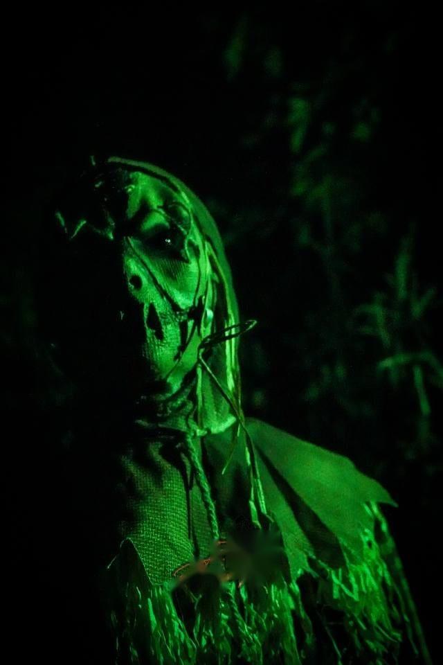 A costumed actor standing among the trees at the Haunted Forest attraction